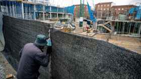 Un hombre mira por el agujero de una lona de una obra en construccin / Carlos Lujn (Europa Press)