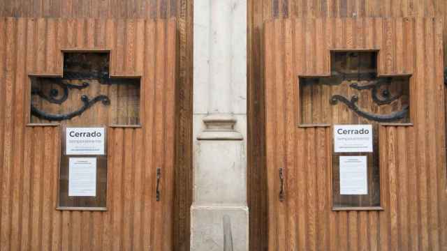 Cruces en la puerta de una iglesia con el cartel de 'Cerrado temporalmente'. /EP