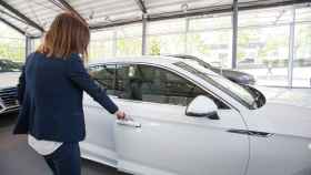 Una mujer abre un coche aparcado en el interior de un concesionario. / EP