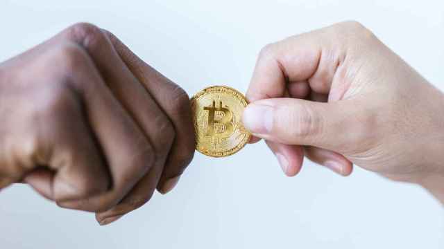Dos manos sujetando un Bitcoin / PEXELS