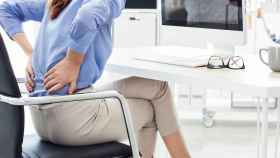 Una mujer se queja de dolor de espalda tras pasar varias horas sentada frente al ordenador / EP