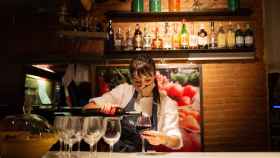 Una camarera sirve una copa de vino en el interior de un bar. / EP