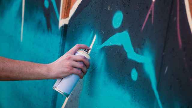 Un artista callejero haciendo un grafiti.