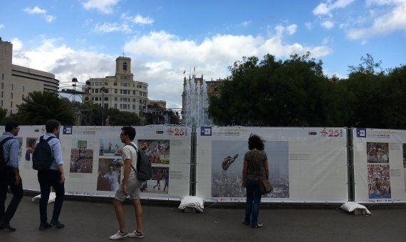 Ciudadanos observan el mural con fotografías olímpicas que rodeaba plaça Catalunya / M.S.