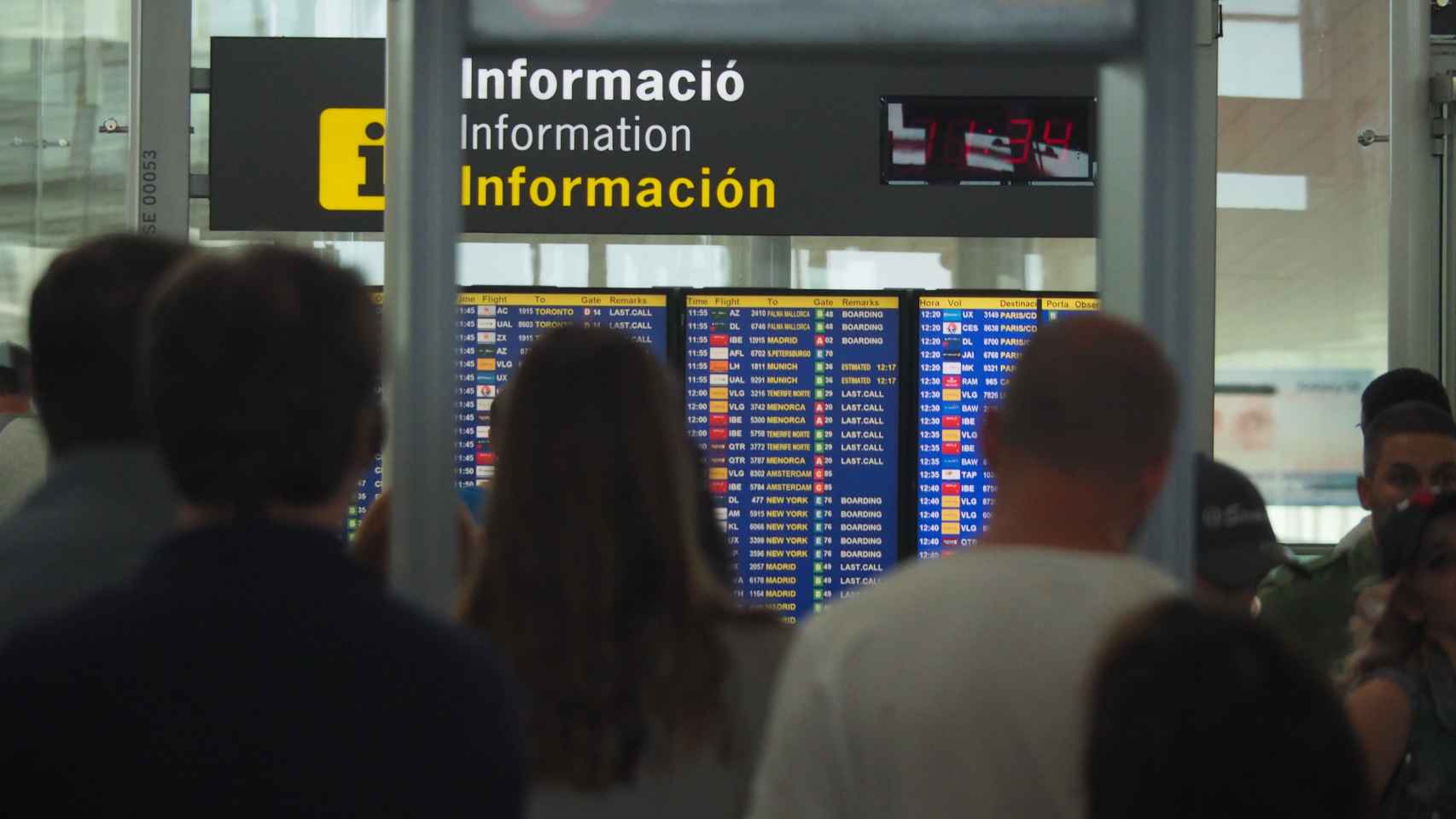Pasajeros del Aeropuerto de Barcelona consultando los paneles de información / ARNAU MAS