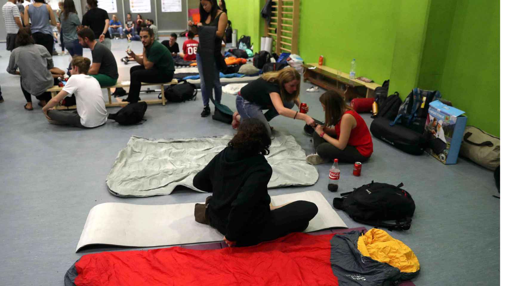 Jóvenes preparan colchonetas y demás útiles para dormir en la Escuela Jaume I / EFE - TONI ALBIR