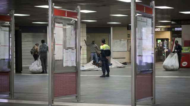 Manteros en la estación de Plaza Catalunya vigilados por un Mosso d'Esquadra / HUGO FERNÁNDEZ