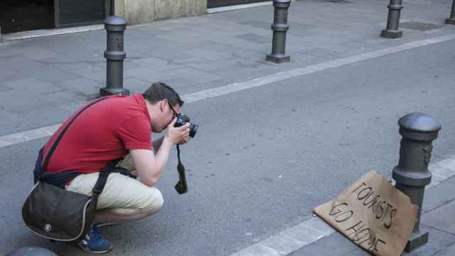 Un turista fotografía un cartel contrario a la llegada de turistas a Barcelona / ÁLVARO VENTURA
