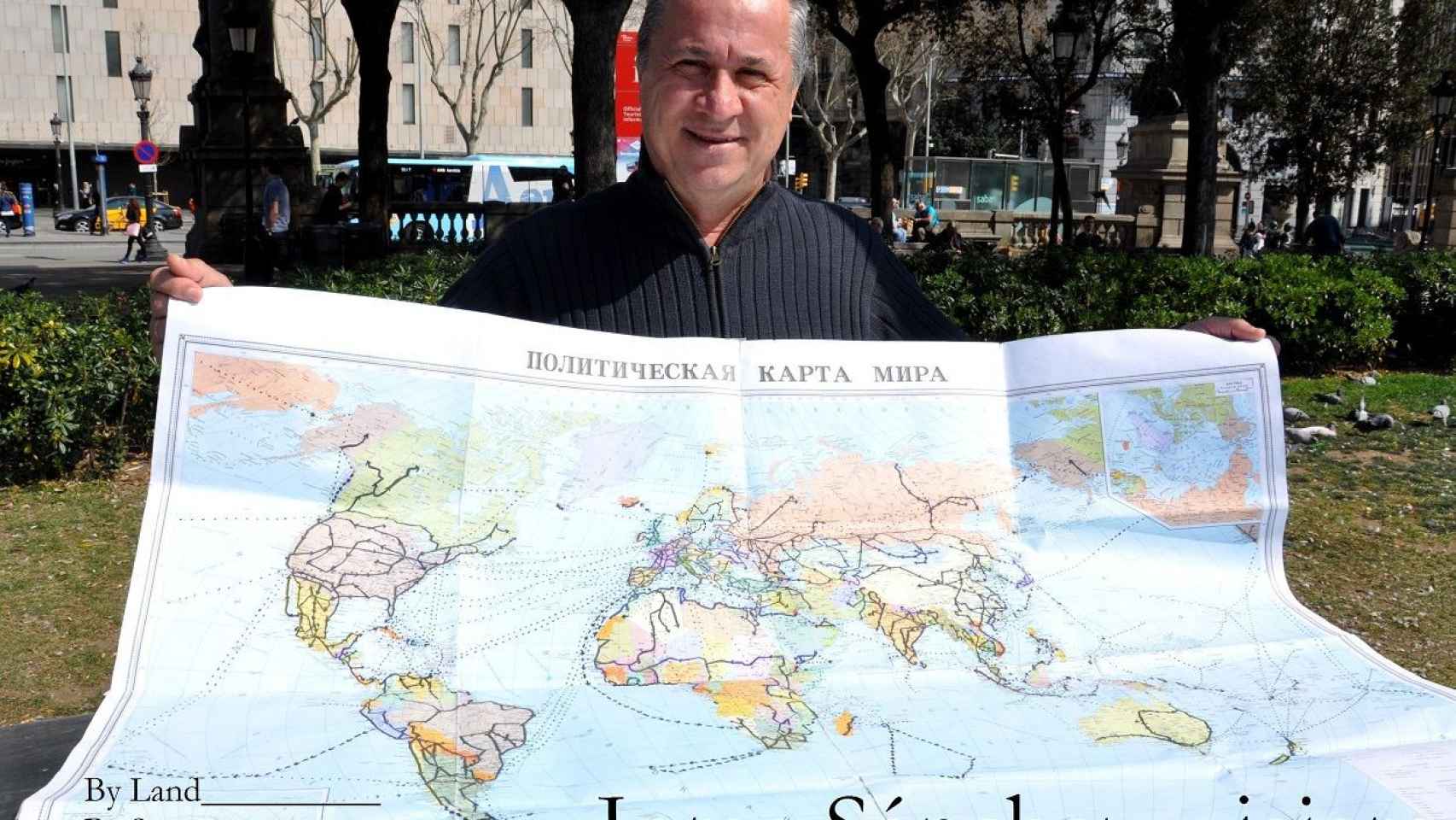 Jorge Sánchez sostiene, en la Plaça Catalunya de Barcelona, el mapa ruso donde anota todos los viajes que ha realizado a lo largo de su azarosa vida / MIKI