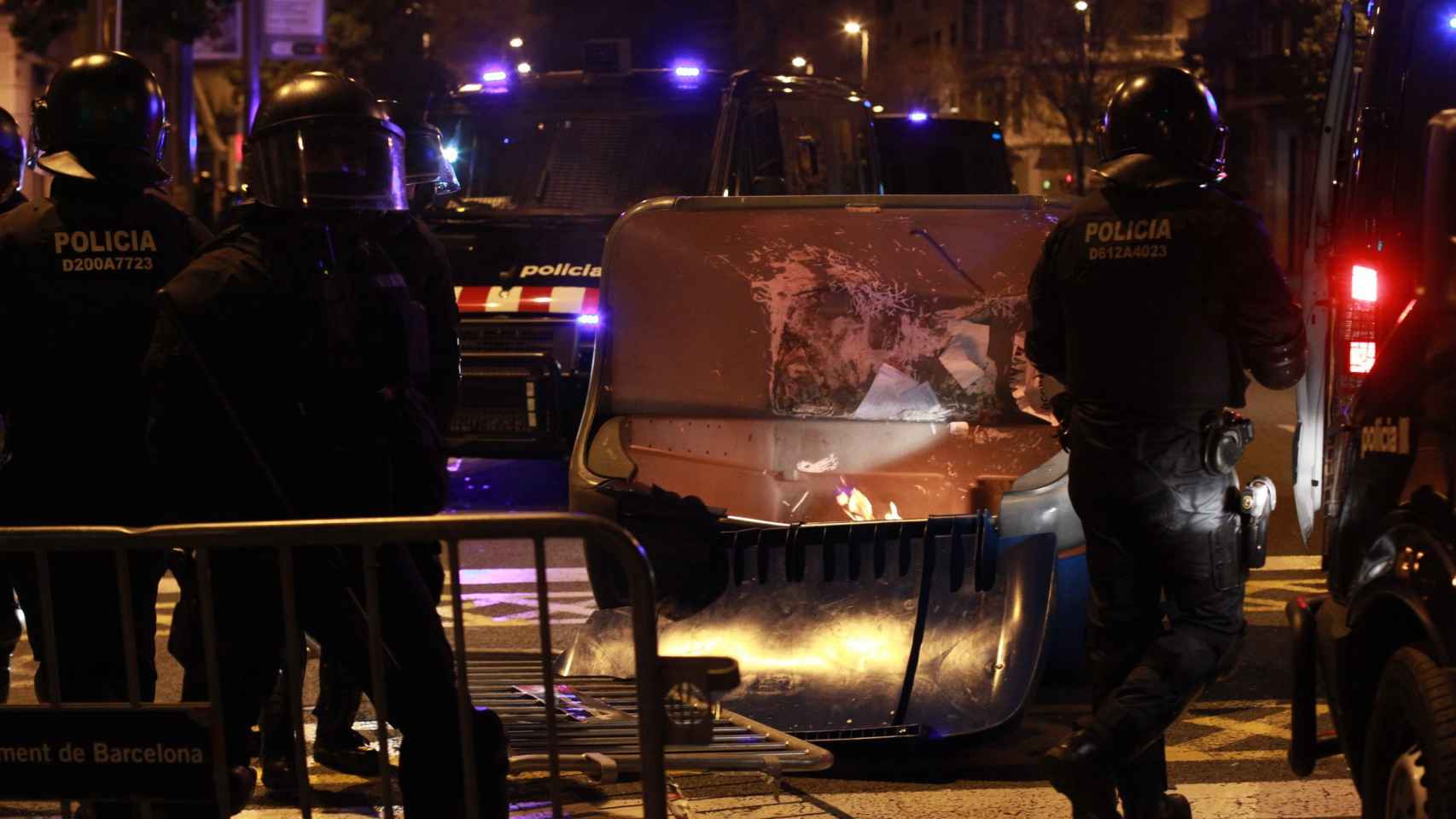 Mossos d'Esquadra junto a un contenedor quemado en una calle del Eixample durante las protestas tras el arresto de Puigdemont / HUGO FERNÁNDEZ