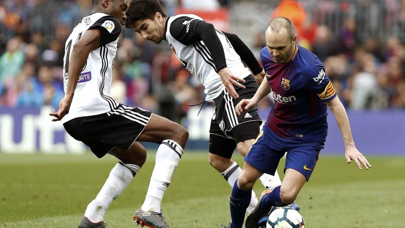 Iniesta controla el balón el balón ante dos jugadores del Valencia / EFE