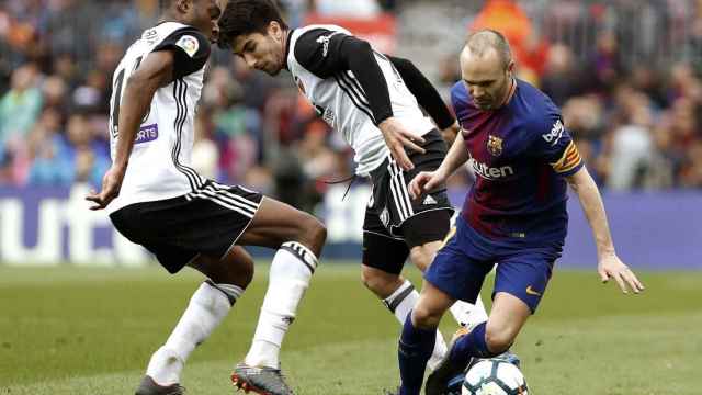 Iniesta controla el balón el balón ante dos jugadores del Valencia / EFE