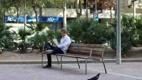 Imagen de archivo de un hombre leyendo en una plaza en Barcelona | HUGO FERNÁNDEZ