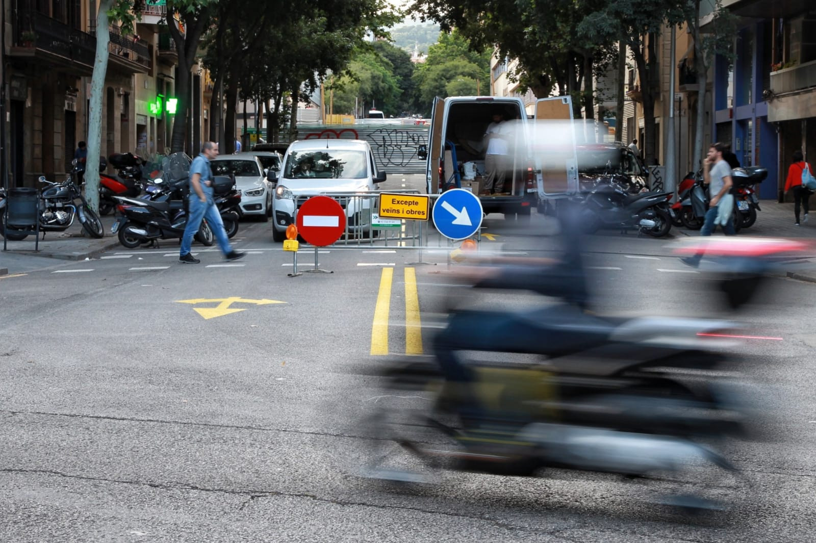 Una moto pasa por Mallorca con una valla al fondo que corta la calle de Nàpols / HUGO FERNÁNDEZ