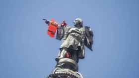 Dos activistas subidos al monumento de Colón para colocar el chaleco / HUGO FERNÁNDEZ