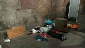 Una persona durmiendo en una calle del Raval rodeada de basura
