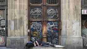 Durmiendo en un portal pintado con grafitis en la calle Ferran / HUGO FERNÁNDEZ