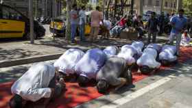 Taxistas musulmanes rezando en una alfombra en Paseo de Gràcia | HUGO FERNÁNDEZ