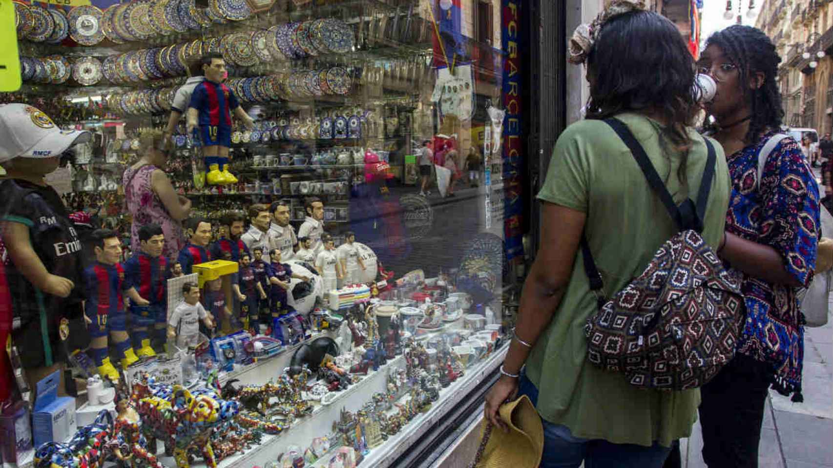 Turistas frente a un escaparate con souvenirs en la calle Ferran / HUGO FERNÁNDEZ