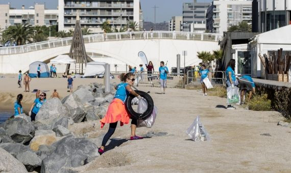 Una voluntaria retira una rueda de la playa de la Mar Bella / HUGO FERNÁNDEZ 