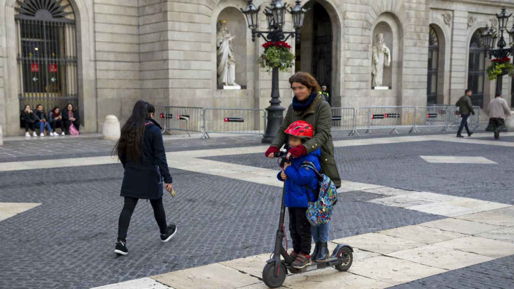 Una mujer y niño pasan por Sant Jaume en patinete / HUGO FERNÁNDEZ