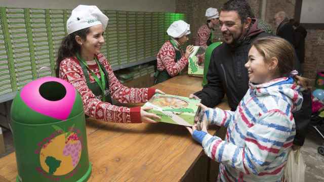 Una mujer entrega a una niña un roscón a cambio del reciclaje de botellas de vidrio / ECOVIDRIO