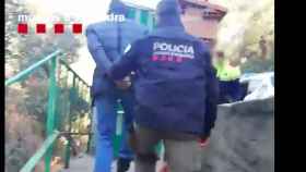 Un agente de Mossos se lleva detenido a uno de los posibles miembros de la banda de ladrones contorsionistas / TWITTER MOSSOS
