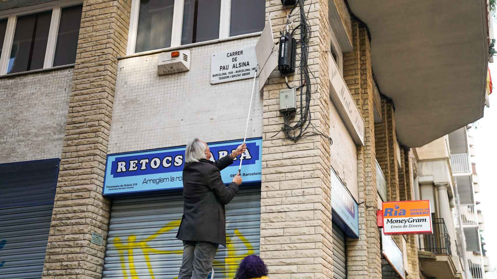 Un vecino cambiando el nombre de la calle por Pau Alsina en Gràcia / AYUNTAMIENTO
