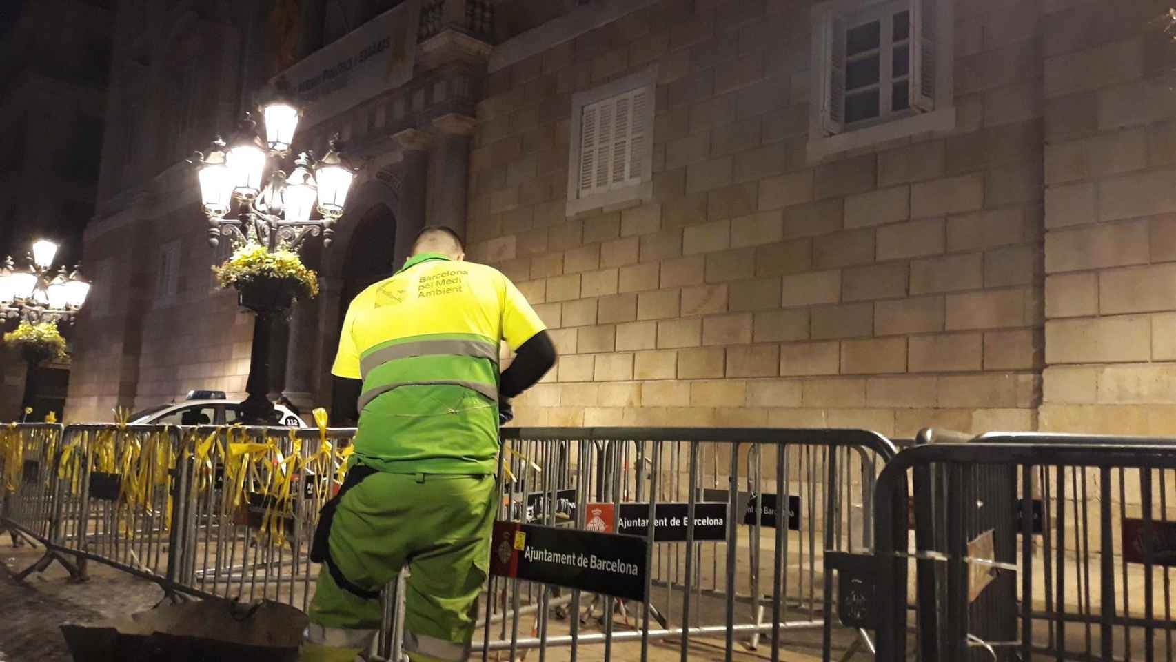 Un empleado municipal quita los lazos amarillos de las vallas de la Plaza Sant Jaume / EUROPA PRESS