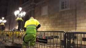 Un empleado municipal quita los lazos amarillos de las vallas de la Plaza Sant Jaume / EUROPA PRESS