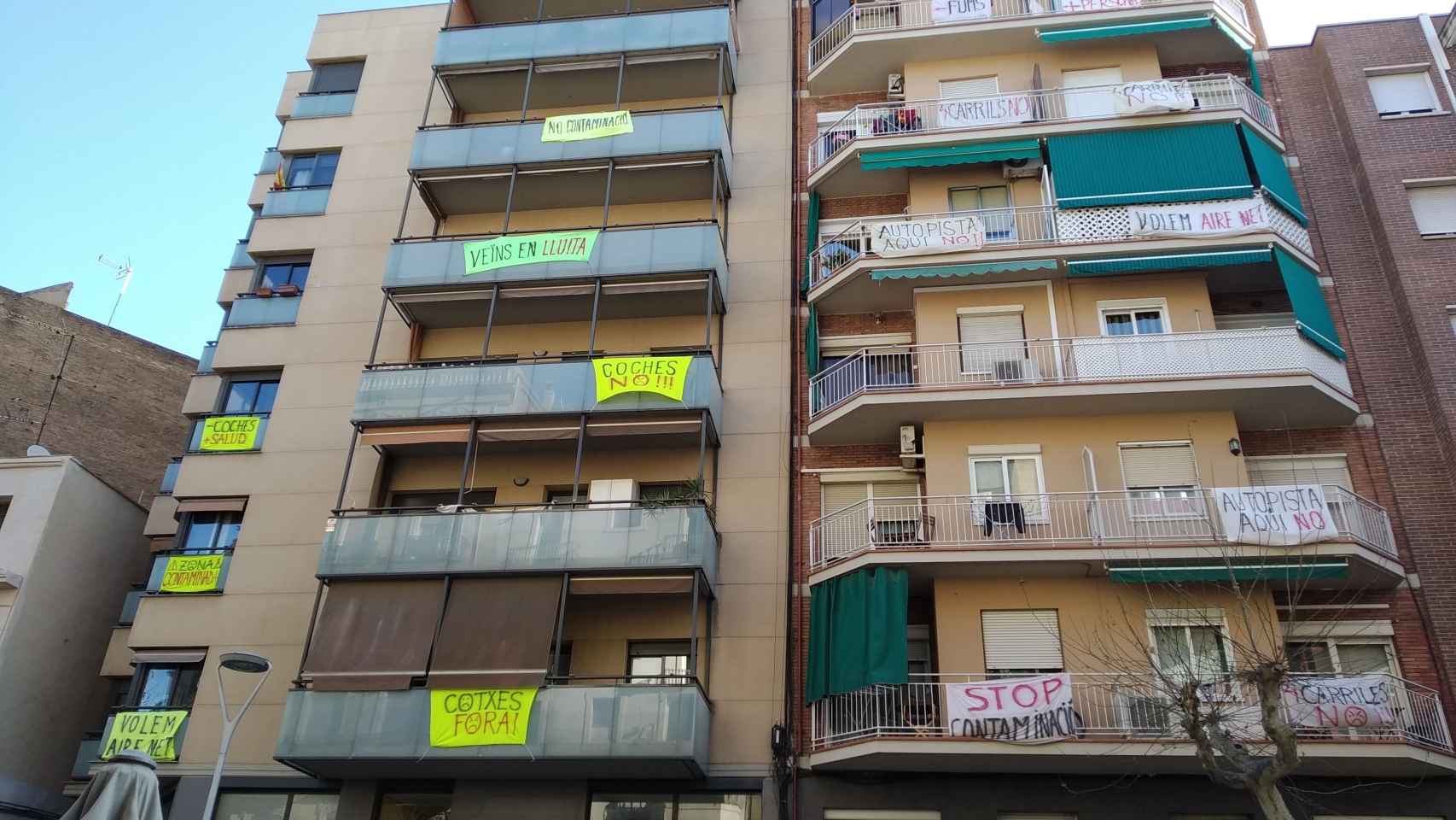 Bloques de viviendas de la calle de Independència, en el Clot, con pancartas contra el aumento de carriles de circulación / JORDI SUBIRANA