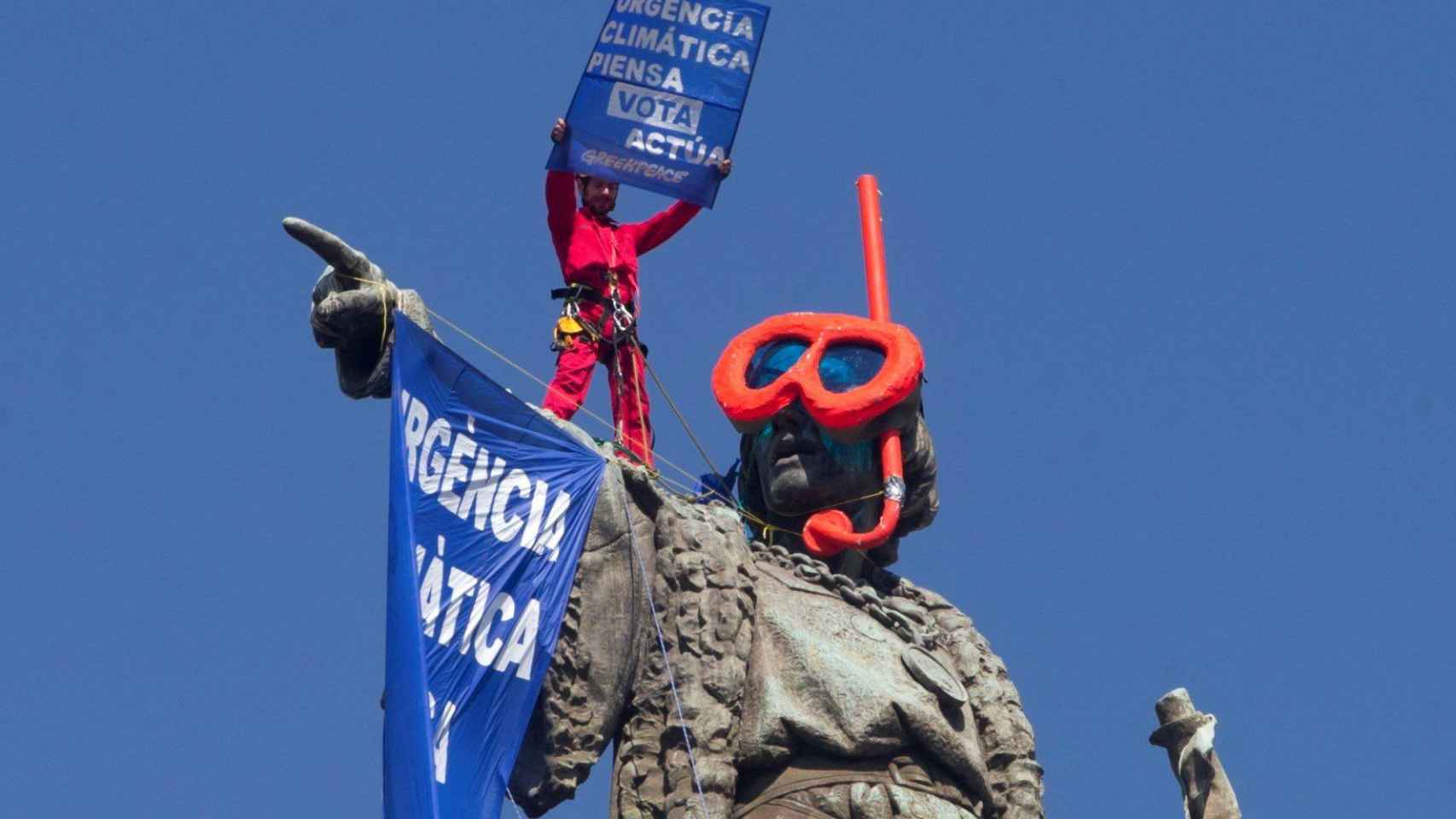 Activista de Greenpeace ondeando una pancarta en la estatua de Colón / EFE