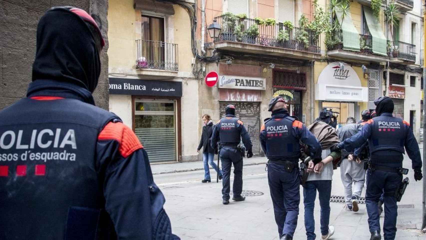Agentes de los Mossos d'Esquadra con un detenido en un operativo contra los narcopisos en Barcelona / HUGO FERNÁNDEZ