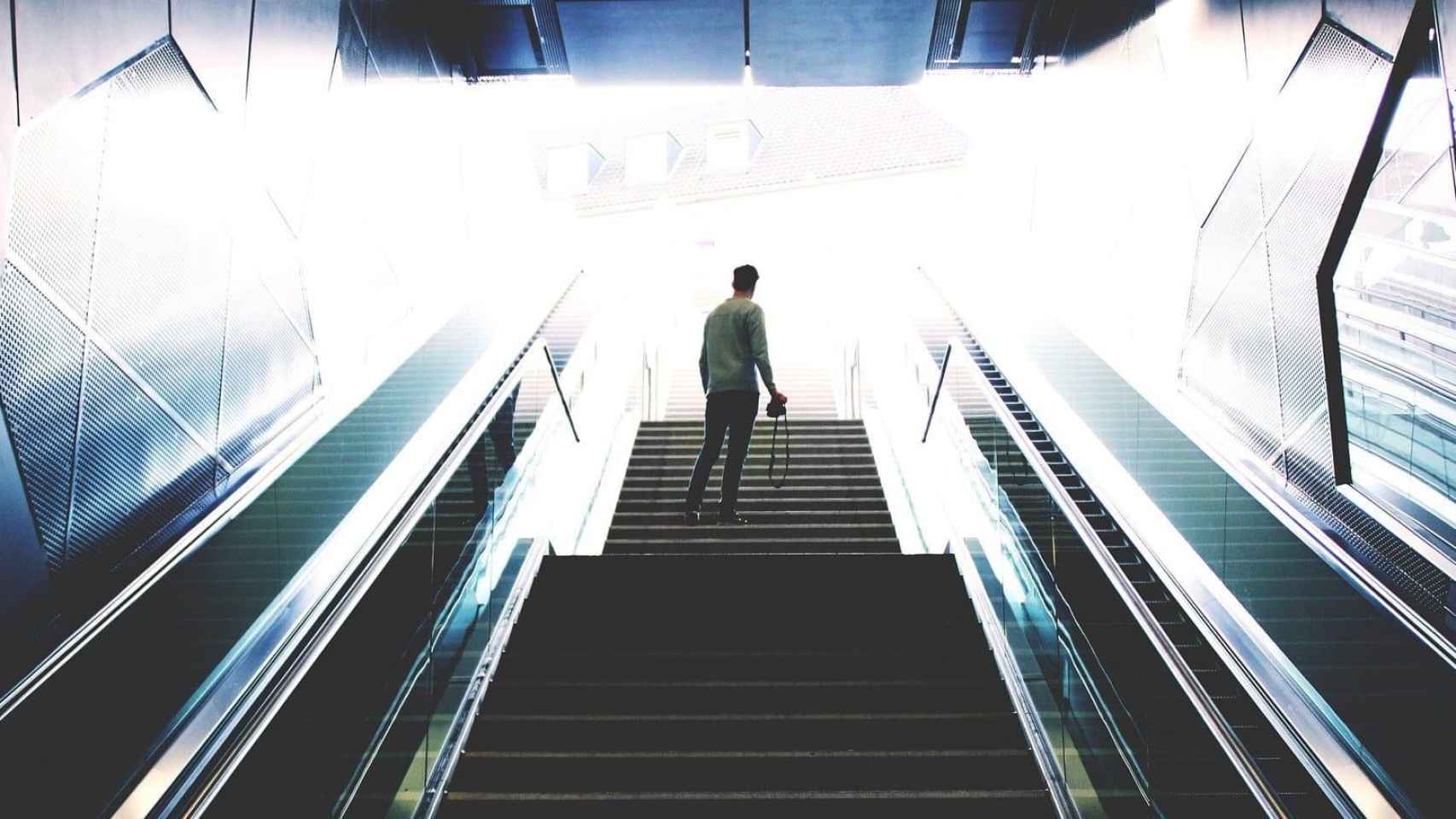 Un hombre de espaldas junto a dos escaleras mecánicas del metro