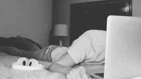 Un joven durmiendo en una habitación de un hotel con un portátil enfrente / Archivo
