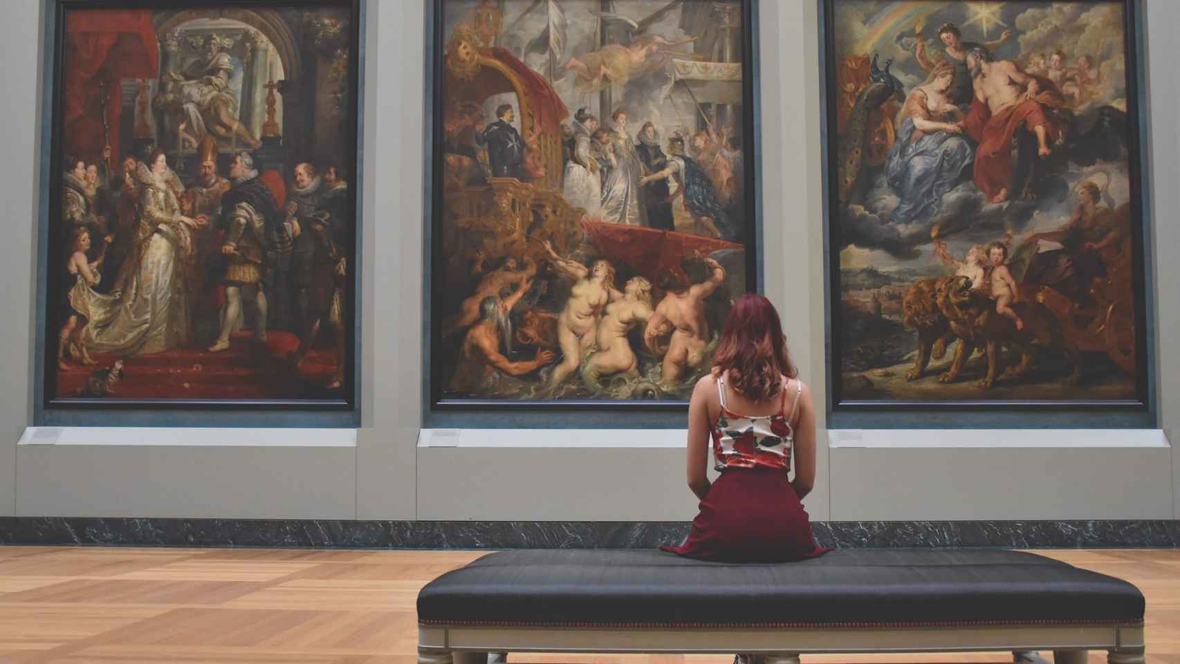 Una chica admirando tres pinturas en el Louvre, uno de los museos más famosos del mundo / PIXABAY
