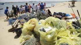 Bolsas llenas de plástico en la orilla del mar / Coca-Cola
