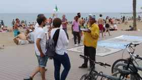 Un vendedor ofrece mojitos a unos turistas en la playa de la Barceloneta / JORDI SUBIRANA