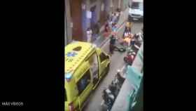 Algunas personas atienden al anciano junto a una ambulancia en el Raval.