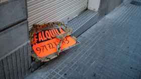 Un cartel de 'se alquila' roto y descolgado en el suelo de Barcelona