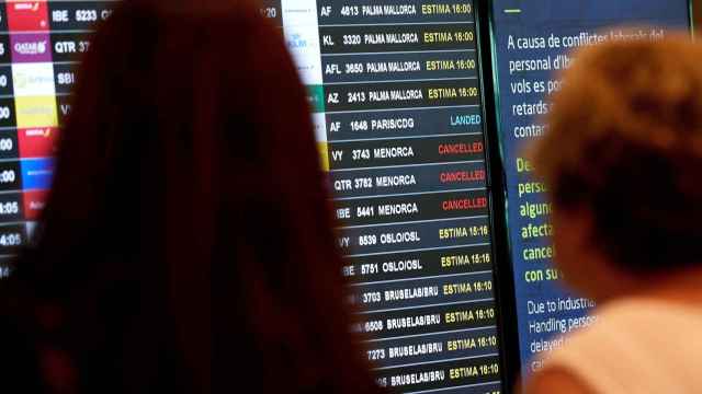 Dos viajeras miran el panel de los vuelos en el aeropuerto de Barcelona, este sábado / EFE