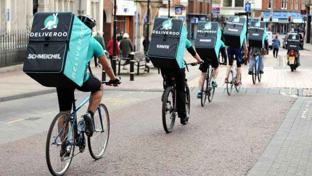 Repartidores de la compañía Deliveroo pedaleando en la calle