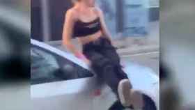 Una mujer subida en el capó de un coche en Poblenou