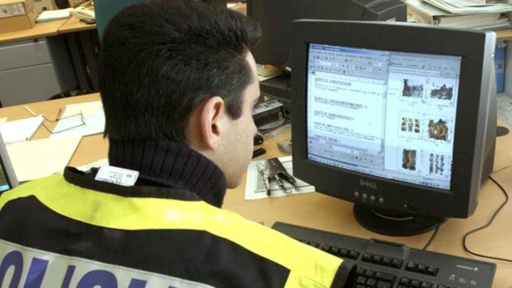 Un agente de la Policía Nacional delante de un ordenador investigando el material incautado / EFE