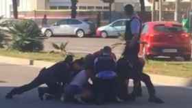 Una decena de agentes policiales intentando reducir al hombre en el paseo de la Zona Franca de Barcelona
