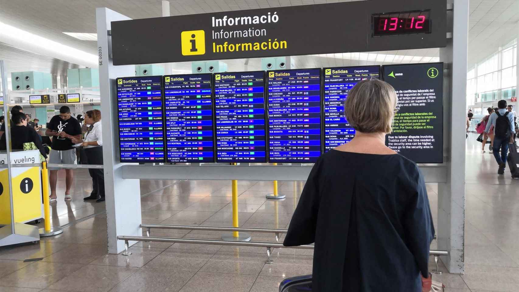 Una usuaria del Aeropuerto de Barcelona observando un panel informativo durante la jornada de huelga de los trabajadores de seguridad / EP