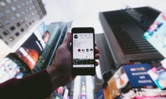 Un usuario de Instagram sujetando un teléfono con varios rascacielos de fondo