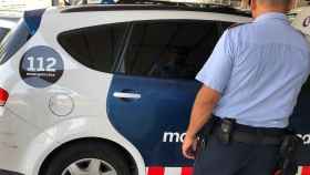 Agente de los Mossos d'Esquadra ante un vehículo policial investigando el robo al cantante argentino / EUROPA PRESS