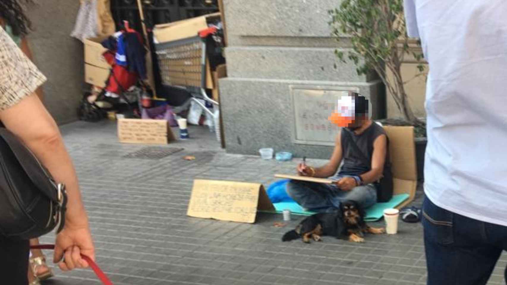 Un mendigo pide dinero acompañado por su perro en las calles de Barcelona / MA