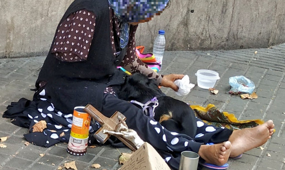 Una mendiga pide dinero en las calles de Barcelona acompañada por su perro